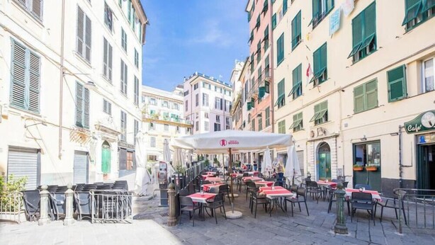 A street with outdoor seating, buildings with shutters, and a cafe sign. - Aquarium 5'| 1BR | A/C| By Tilo (Genoa)