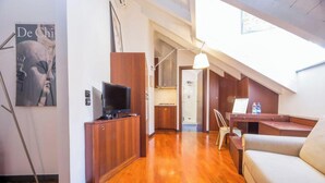A compact living space with a wooden cabinet, a television, a desk, and a sofa. - Aquarium 5'| 1BR | A/C| By Tilo (Genoa)