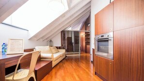 A modern kitchen with wooden cabinets, a built-in oven, and a dining area with a wooden table and chairs. - Aquarium 5'| 1BR | A/C| By Tilo (Genoa)