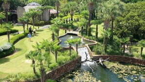 Un campo da golf con uno stagno, palme e un ponte di pietra.