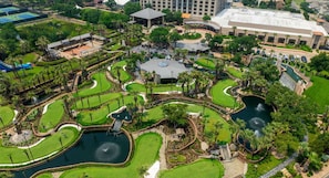 Luftaufnahme eines Golfplatzes mit mehreren Grüns, Wasserflächen und umliegenden Gebäuden.