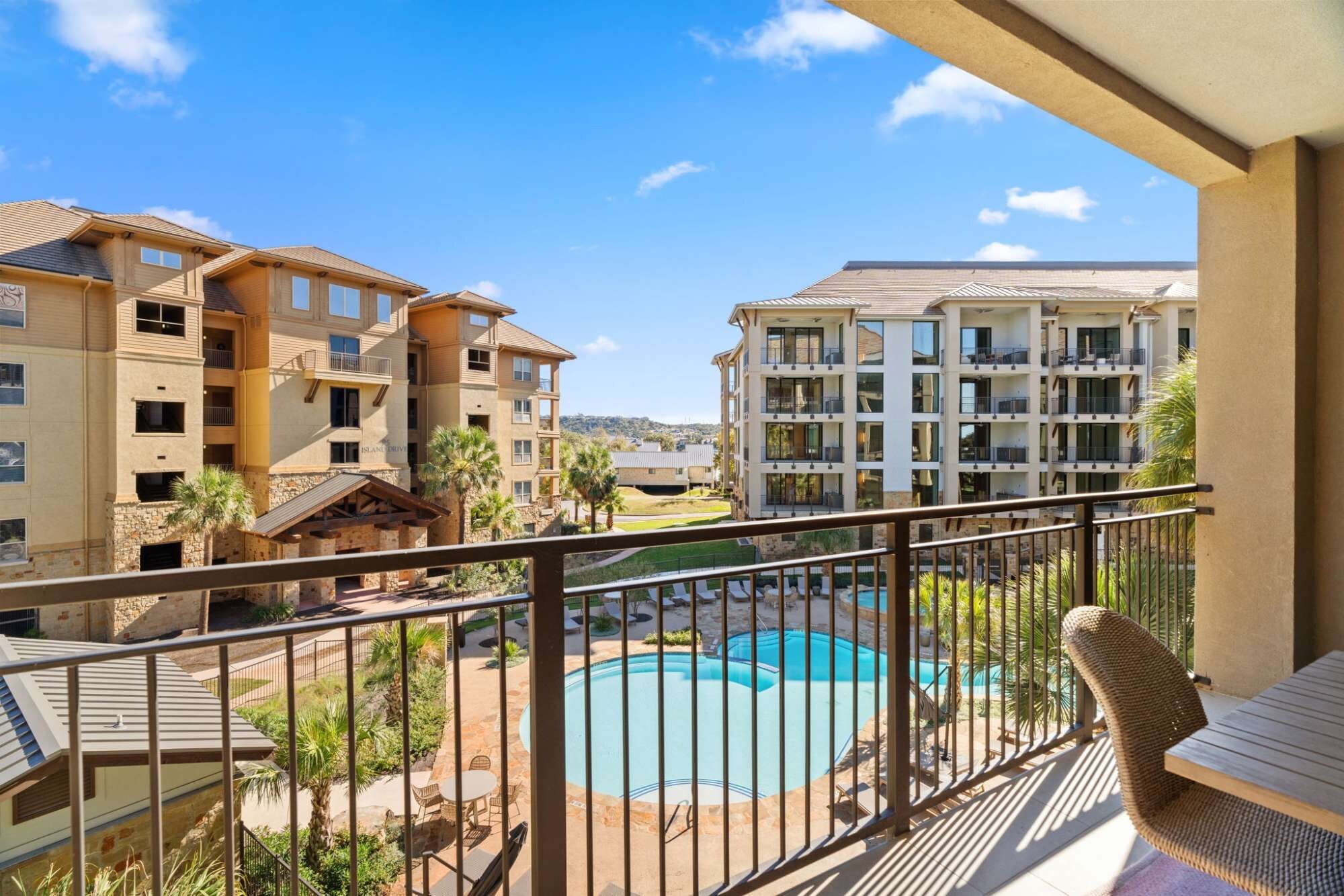 A residential building with a swimming pool, balconies, and a view of the surrounding area.