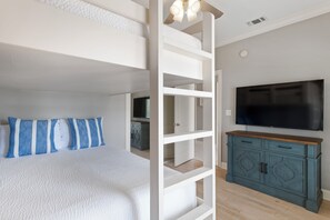Une chambre avec un lit superposé, une télévision et une armoire.