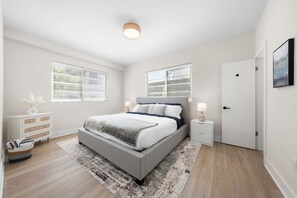 A bedroom with a bed, bedside tables, a dresser, a door, and a window. - Chic Sobe Retreat 2-bedroom 2 full bath apartment walk to Lincoln Rd & Bay (Miami Beach)