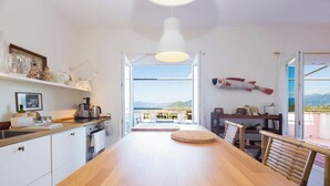 Een moderne keuken met een houten tafel en stoelen, een hanglamp en uitzicht op de omgeving.