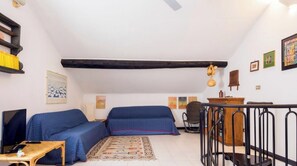 A cozy room with a sofa, a small table, a chair, a wooden cabinet, and a decorative rug. - FinalBorgo | 2BR| WIFI | Historic Village| By Tilo (Finale Ligure)