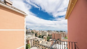 Uma varanda com vista para um horizonte urbano, prédios e céu claro.