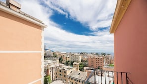 Ein Balkon mit Blick auf eine Stadtlandschaft, Gebäude und einen klaren Himmel.