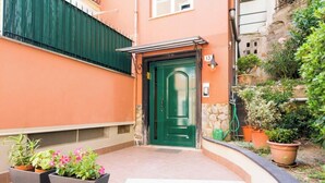 Um edifício com porta verde, parede de pedra e plantas em vasos.