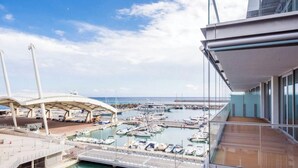Un puerto deportivo con barcos amarrados, un paseo marítimo cubierto y un edificio moderno con grandes ventanales.