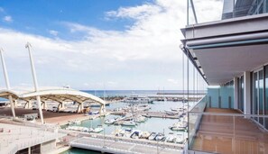 Ein Yachthafen mit anlegenden Booten, ein überdachter Fußweg und ein modernes Gebäude mit großen Fenstern.