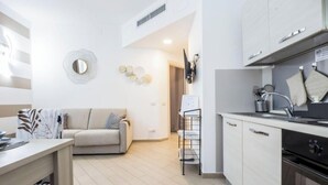 Una cocina moderna con horno empotrado, un comedor con mesa y sillas, un sofá y un espejo decorativo en la pared.