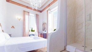 Ein Schlafzimmer mit Bett, Schminktisch, Dusche und Blick ins Freie.