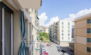 Eine enge Straße mit mehrstöckigen Gebäuden, blauem Himmel und abgestellten Autos.