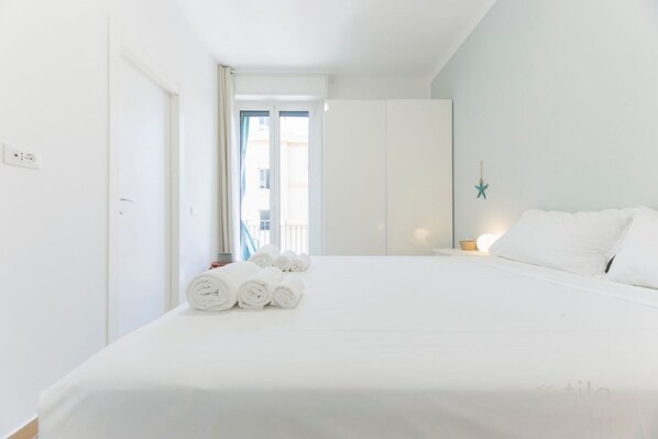 Ein Hotelzimmer mit Bett, Schrank, Nachttisch und Blick nach draußen.