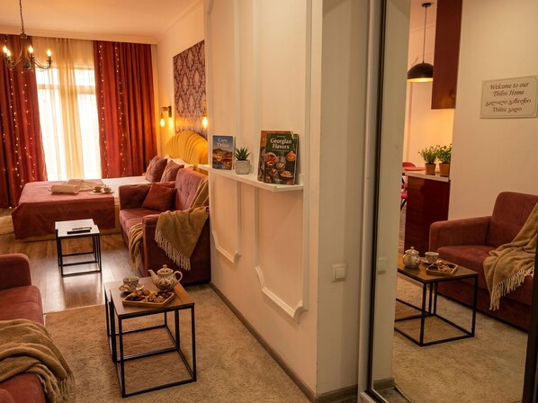 A cozy living room with a sofa, a coffee table, and a bookshelf with books and decorative items. - Riverside Central Apartments (T'bilisi)