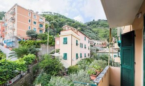 Ein Wohngebäude mit Balkon, umgeben von Grünflächen und weiteren Gebäuden.