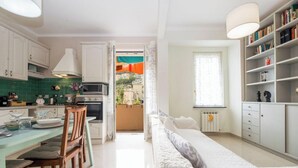 A modern kitchen with white cabinets, a dining table with chairs, and a view of the outside. - Beach 7M| 1BR| Wifi| Nervi Park By Tilo (Genova)