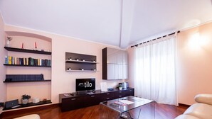 Uma sala de estar moderna com uma mesa de centro de vidro, estantes, uma TV de tela plana e um sofá.