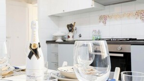 Cozinha com armários brancos, fogão a gás e uma garrafa de vinho.