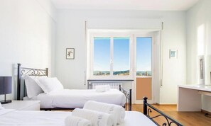Ein Hotelzimmer mit zwei Betten, einem Schreibtisch, einem Sessel, einem Fenster mit Blick und einer Heizung.