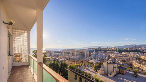 Uma varanda com vista para a paisagem urbana, incluindo edifícios e um corpo d'água ao longe.