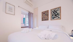 Ein Hotelzimmer mit einem großen Bett, zwei Bildern an der Wand, einem Fenster mit Vorhängen und Blick nach draußen.