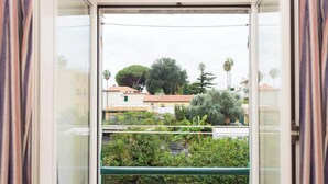 En utsikt från en balkong med ett räcke, med utsikt över ett bostadsområde med hus och träd.