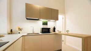A modern kitchen with a microwave, sink, and wooden countertop. - Aquarium 1'| 3BR| A/C|Parking| City Center By TILO (Genova)