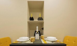 A dining table with white plates, a bottle of champagne, and a candle holder. - City Center 4'|STUDIO|WIFI|BY TILO (Genova)