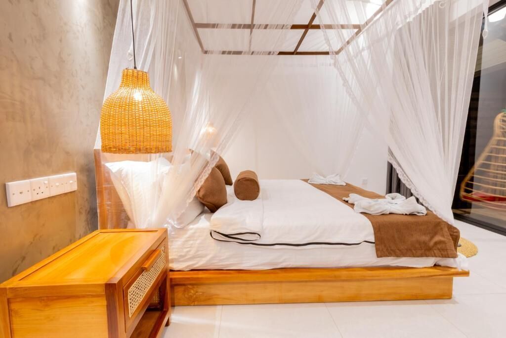 A bed with a canopy, a bedside table, and a hanging light fixture.