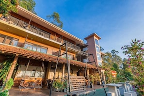 Un edificio de varios pisos con balcón, zona de estar al aire libre y un pequeño jardín.