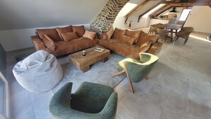 Un soggiorno in stile loft con un divano componibile, un tavolino in legno, un pouf e due poltrone.