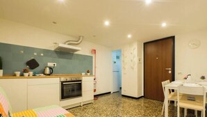 A compact kitchen with a stove, oven, and a microwave. There is a dining table with chairs and a small refrigerator. - AQUARIUM 1'|1BR|A/C| WIFI|BY TILO (Genoa)