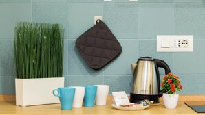 A kitchen counter with a white planter, blue and white cups, a black kettle, and a small potted plant. - AQUARIUM 1'|1BR|A/C| WIFI|BY TILO (Genoa)