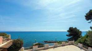 Blick auf das Meer vom Balkon mit Geländer, ein klarer Himmel und der Ozean im Hintergrund.