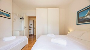 Ein Hotelzimmer mit zwei Betten, einem Kleiderschrank, einem Schreibtisch und einem Stuhl.