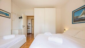 Ein Hotelzimmer mit zwei Betten, einem Kleiderschrank, einem Schreibtisch und einem Stuhl.