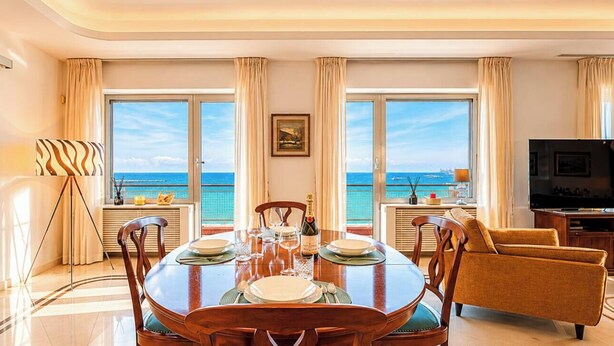 Een eethoek met uitzicht op zee, een televisie en een lamp.