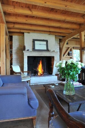 Une pièce chaleureuse avec une cheminée, des meubles en bois et un vase de fleurs.