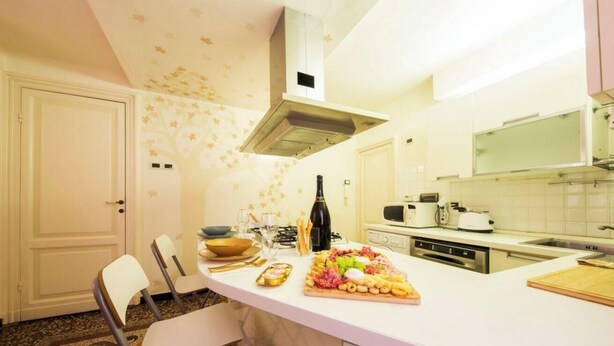 Una cucina con un piano di lavoro bianco, un fornello a gas, un forno a microonde e un lavello.
