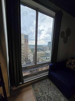 Ein Zimmer mit einem großen Fenster, einem blauen Sofa und einem gemusterten Teppich.