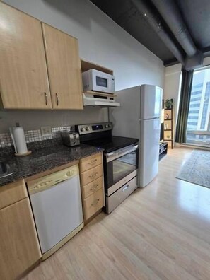 Eine Küche mit Holzausstattung, einer Mikrowelle, einem Backofen und einem Geschirrspüler.
