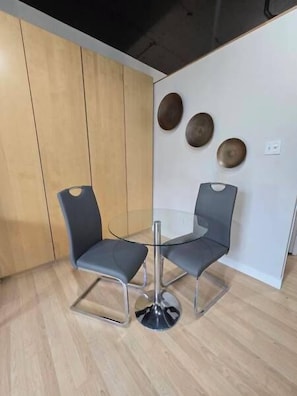 Ein modernes Zimmer mit zwei grauen Sesseln, einem Glastisch, Holzpaneelen und drei dekorativen Tellern an der Wand.