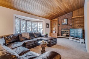 A living room with a leather sofa, a fireplace, and a television.