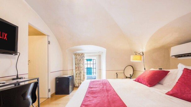 Een hotelkamer met een bed, een bureau, een televisie en een airconditioner.