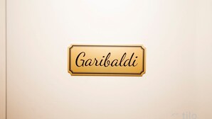Een bord met de naam 'Garibaldi' op een witte muur.