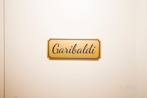 Ein Schild mit dem Schriftzug 'Garibaldi' an einer weißen Wand.