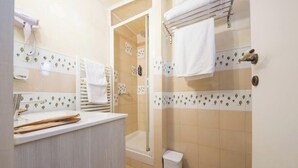 Een badkamer met een douche, een handdoekhouder en een wastafel.
