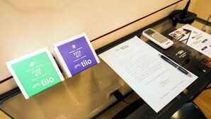 Een receptiebalie met een telefoon, een notitieboekje en twee kaarten met de merknaam TILO.
